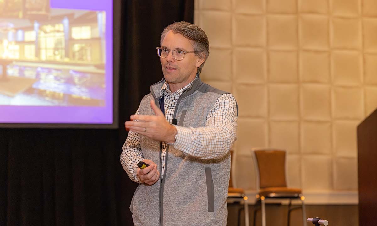Ron Callis in a long sleeve shirt with a grey vest presenting