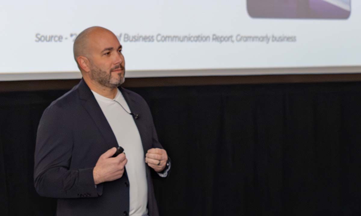 A man in a black suitcoat and white t shirt presenting